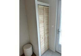 Des portes de placard persiennées en pin massif pour un rangement discret et lumineux